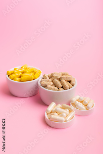 Food supplements, vitamins and minerals in forms of tablets, capsules and multivitamin meds from above on light pink background. Healthy lifestyle and good health thanks to preventative medicine.