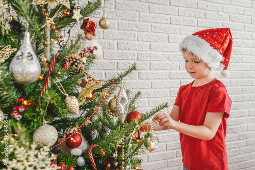 Fotografie Happy child decorating the Christmas tree with balls.