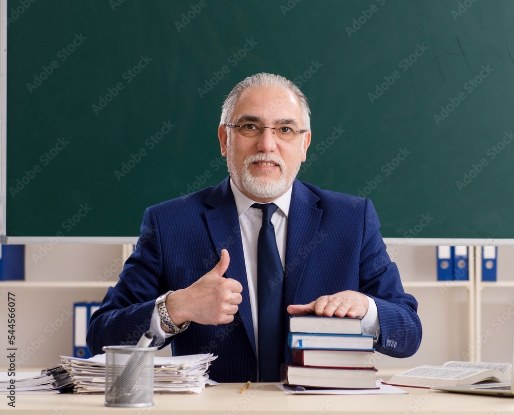 Aged male teacher in front of chalkboard Aged male teacher in front of chalkboard