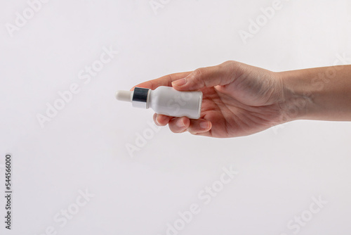 Hand and a white glass dropper bottle on white background