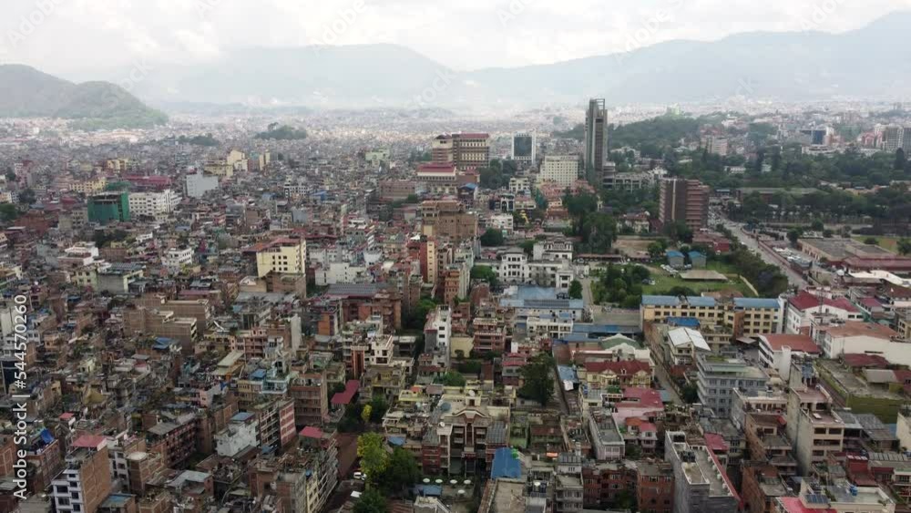 A rising aerial view of the Asian city of Kathmandu, Nepal on a cloudy day with lots of haze and pollution.