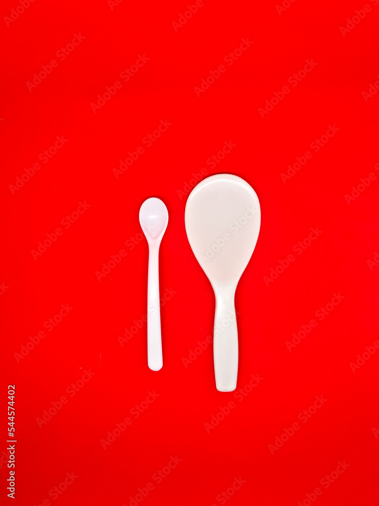 white centong and white spoon Red Background white centong and white spoon Red Background