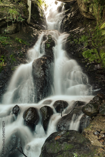 Vertical long exposure shot of waterfall in the mountains. Time concept. Water movement. Mountainous environment.