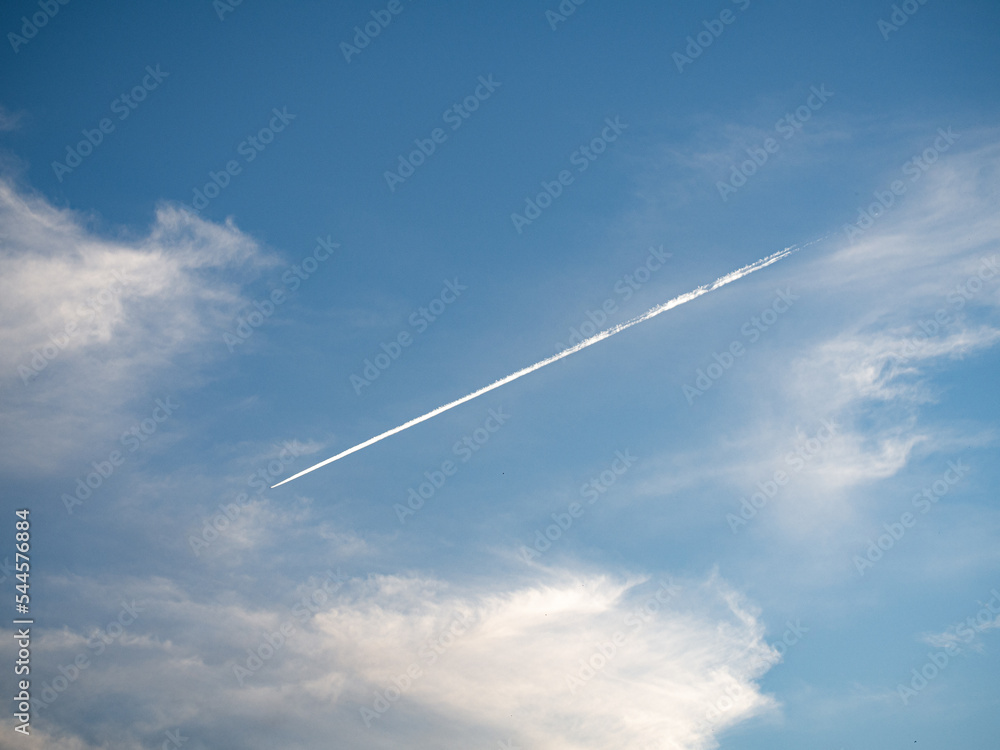 Wake of a plane in a cloudy blue sky Wake of a plane in a cloudy blue sky