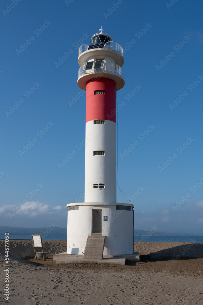lighthouse on beach dunes with clear skies