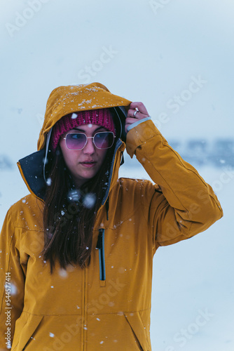 woman in the snow with yellow coat, hat and sunglasses