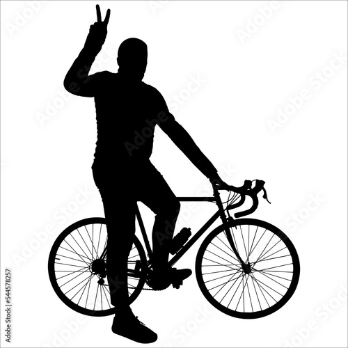 The cyclist poses for the camera. The man and the bicycle are sideways. The guy is standing near the bike, holding the steering wheel with one hand; the second-hand shows the gesture of "victory".