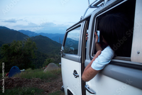 Camper van on the mountain with young girl looking at the view from the car window.