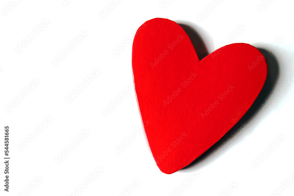 Red lacquered heart shaped box on the right of a white surface with copy space on the left. Horizontal.