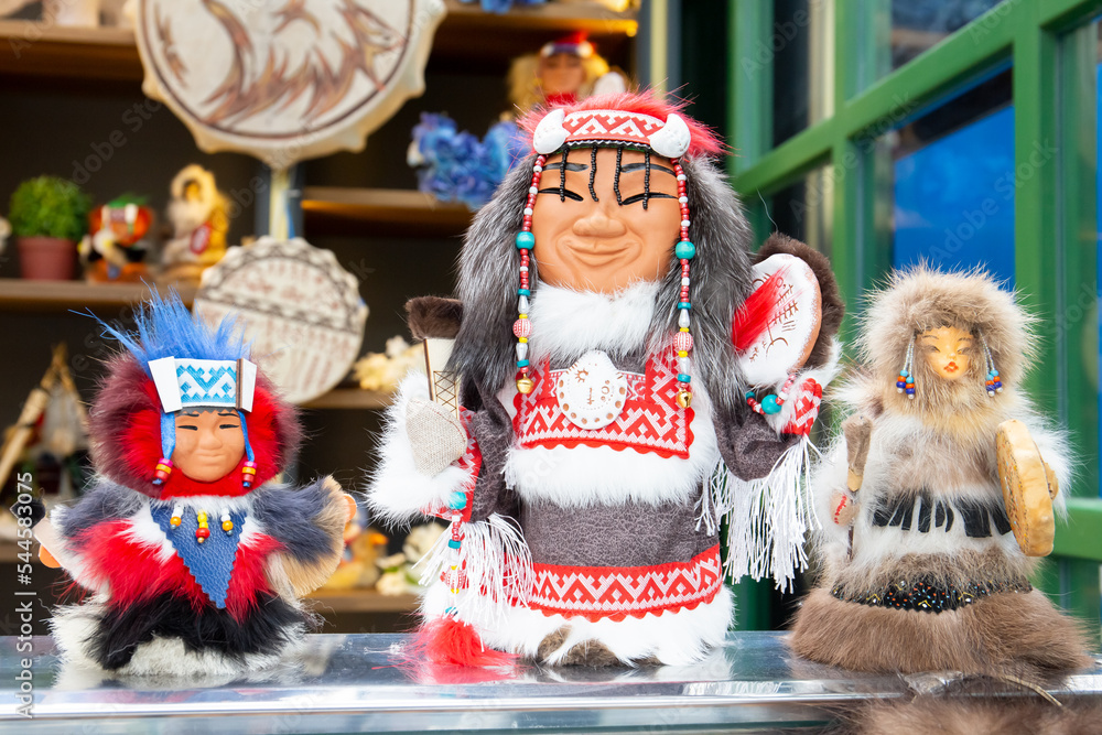 Three toys in national winter clothes are on the table. Ethnic costumes of the peoples of the North of Russia.