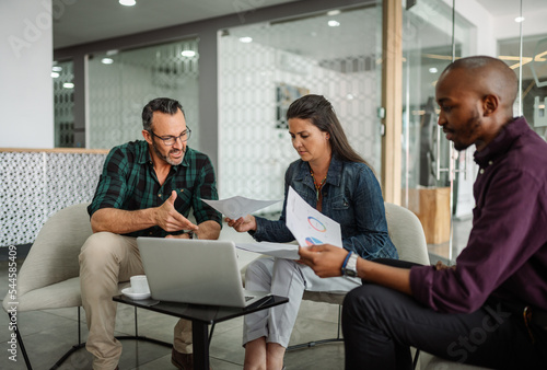 Casual meeting of smiling diverse business team analyzing financial data