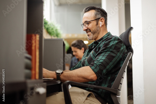 Foto Business man sitting at hot desk in co working office space