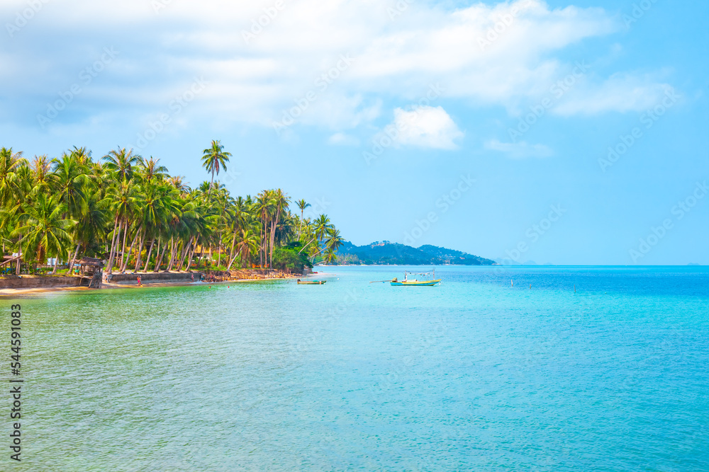 Sea tropical landscape. Sea with boats and sandy shore with palm trees on Koh Samui in Thailand. Travel and tourism