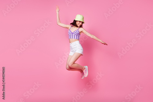 Fototapeta Full size photo of cheerful lady tourist jumping high hands aside isolated paste