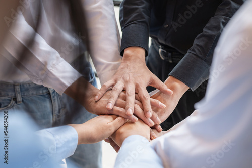 Group of business people putting their hands working together on wooden background in office. group support teamwork agreement concept