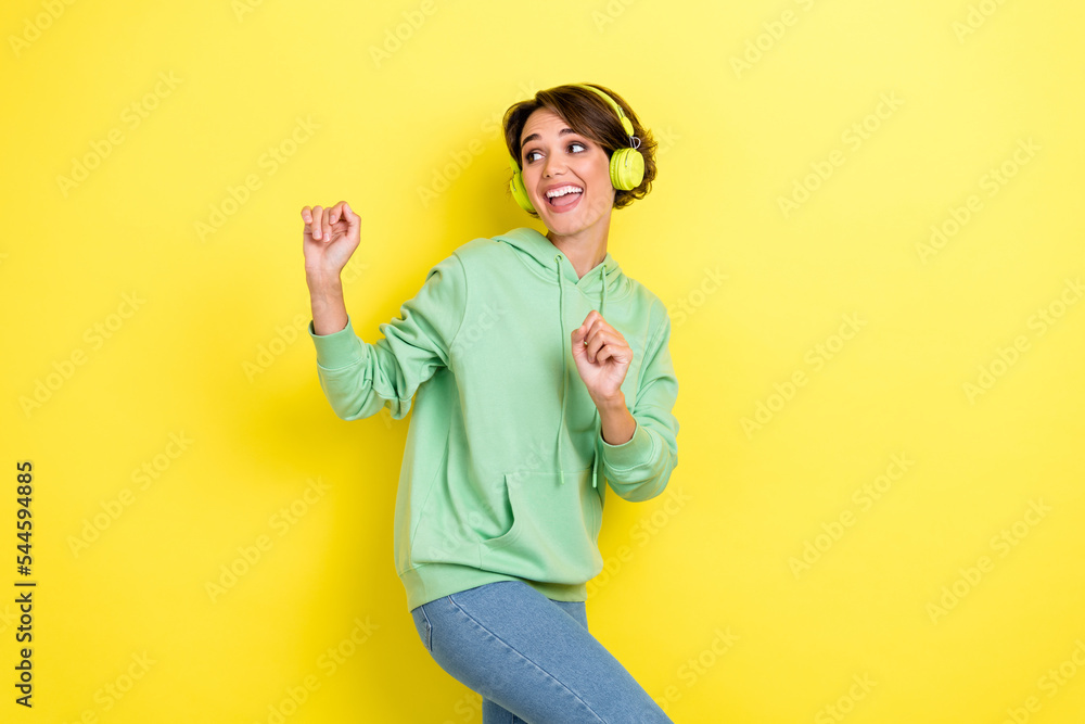 Portrait of cheerful positive satisfied woman with bob hairdo green hoodie dancing look empty space isolated on yellow color background Portrait of cheerful positive satisfied woman with bob hairdo green hoodie dancing look empty space isolated on yellow color background