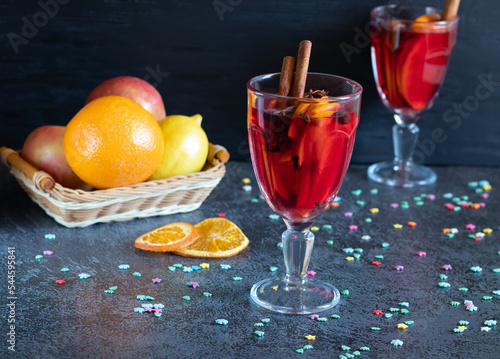 Two glasses of mulled wine, fruits and small snowflakes on dark background. photo