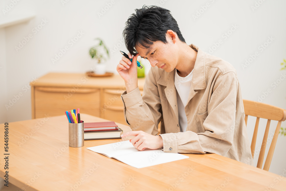 自宅で勉強する若い日本人男性 自宅で勉強する若い日本人男性