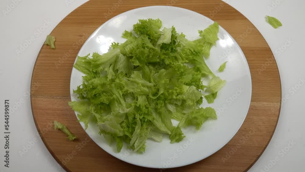 Pieces of lettuce leaves, slices of yellow and red cherry tomatoes, and red onions fall on a white plate, reparation of vegetable salad. Pieces of lettuce leaves, slices of yellow and red cherry tomatoes, and red onions fall on a white plate, reparation of vegetable salad.