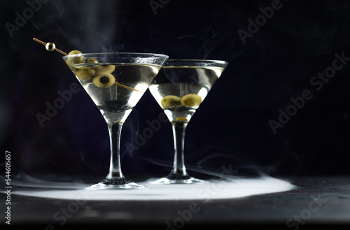 A martini in a triangular glass with olives is on the table