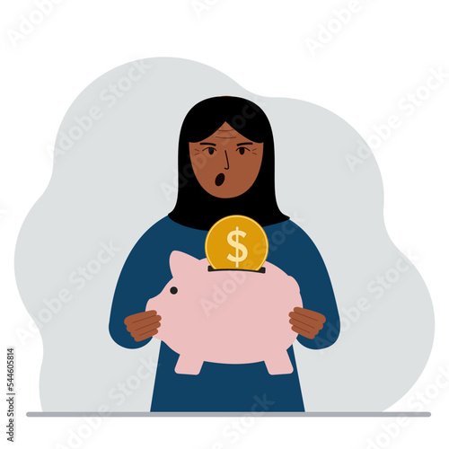 Screaming muslim woman holds a piggy bank, a coin falls into the piggy bank. The concept of saving finance, savings, investing finances.
