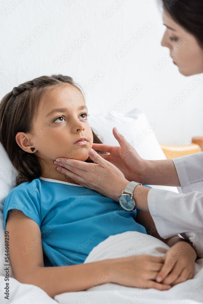 Blurred doctor examining neck of kid on hospital bed. Blurred doctor examining neck of kid on hospital bed.