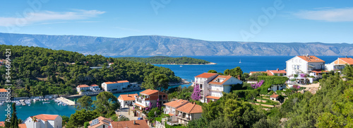 Panoramic view of Jelsa, Hvar island in Croatia. Scenic summer day banner image, bird view from hill. Jelsa bay, seaside marina. Red roofs of traditional buildings.