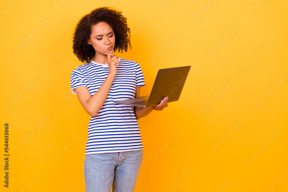 Photo of minded pensive girl hand touch chin look interested laptop decide isolated on yellow color background Photo of minded pensive girl hand touch chin look interested laptop decide isolated on yellow color background