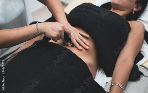 A woman undergoes a radiofrequency treatment on her belly to rejuvenate her skin. Scars, blemishes, and cellulite or fat accumulation in the body.