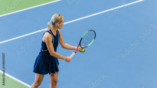 Female Tennis Player About to Serve by Hitting Ball with a Racquet During Championship Match. Technical Woman Athlete Preparing to Strike. World Sports Tournament. High Angle Medium Shot Photo. © Gorodenkoff