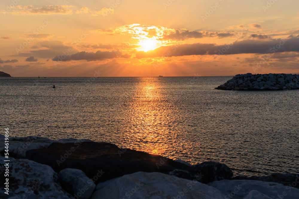 Fototapeta premium Orange sunset sky and sun over the sea. Water surface and outlines on the horizon.
