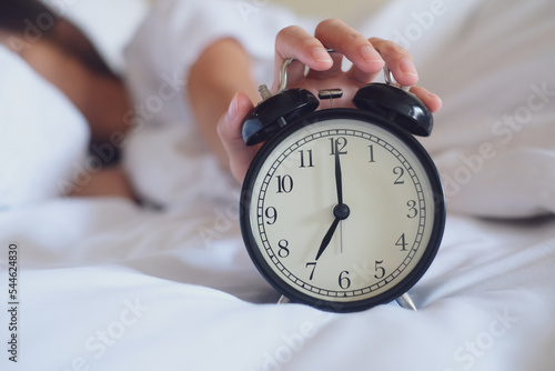 Hand turns off the alarm clock waking up at morning .