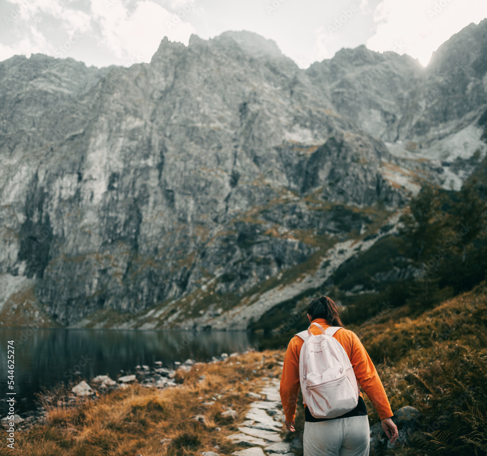 Fototapeta premium A beautiful brunette woman is hiking in the mountains of Europe. Young girl relaxing in the Tatra Mountains. Concept of a healthy active life outdoor