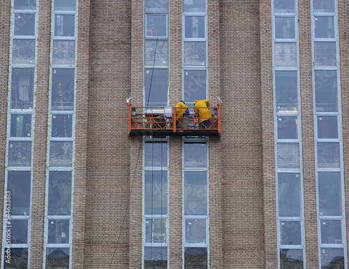 Two workers in a construction cradle on a brick wall of a house, Iskrovsky Prospekt, St. Petersburg, Russia, November 2022 photo