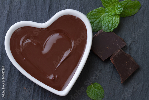 Delicious chocolate mousse with mint in heart-shaped bowl on dark background photo