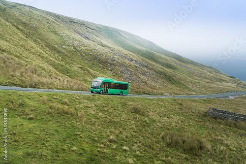 Electric rural bus on the road in the Yorkshire Dales National Park landscape with a blue sky and mountains photo