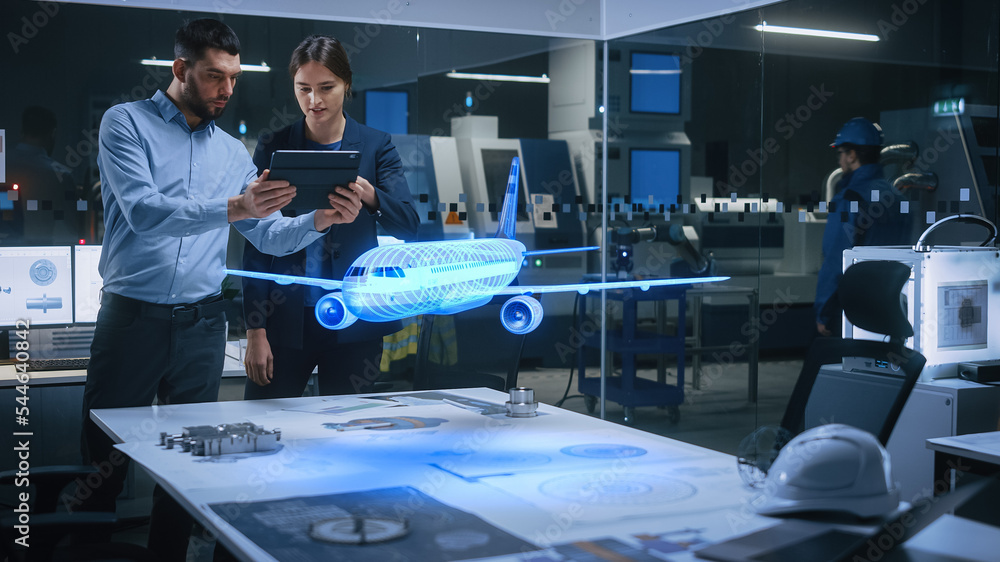 Aeronautics Factory Office Meeting Room: Engineer Holds Tablet Computer, Showing Augmented Reality Airplane Jet Engine to a Female Manager. Modern Industry 4.0 Research and Development Test. - obrazy, fototapety, plakaty 