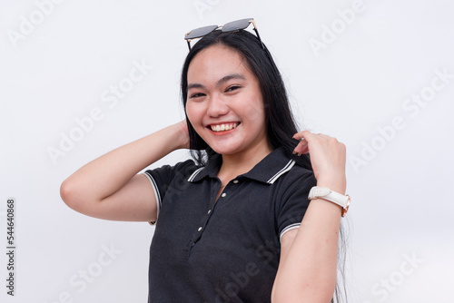 A cheerful Filipino woman with strong long hair in her early 20s. Wearing a black polo shirt. Isolated on a white background.