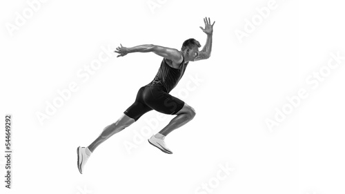 Black and white portrait of muscular male athlete, runner, jogger in motion isolated on white background. Monochrome. Sport, beauty, power and style