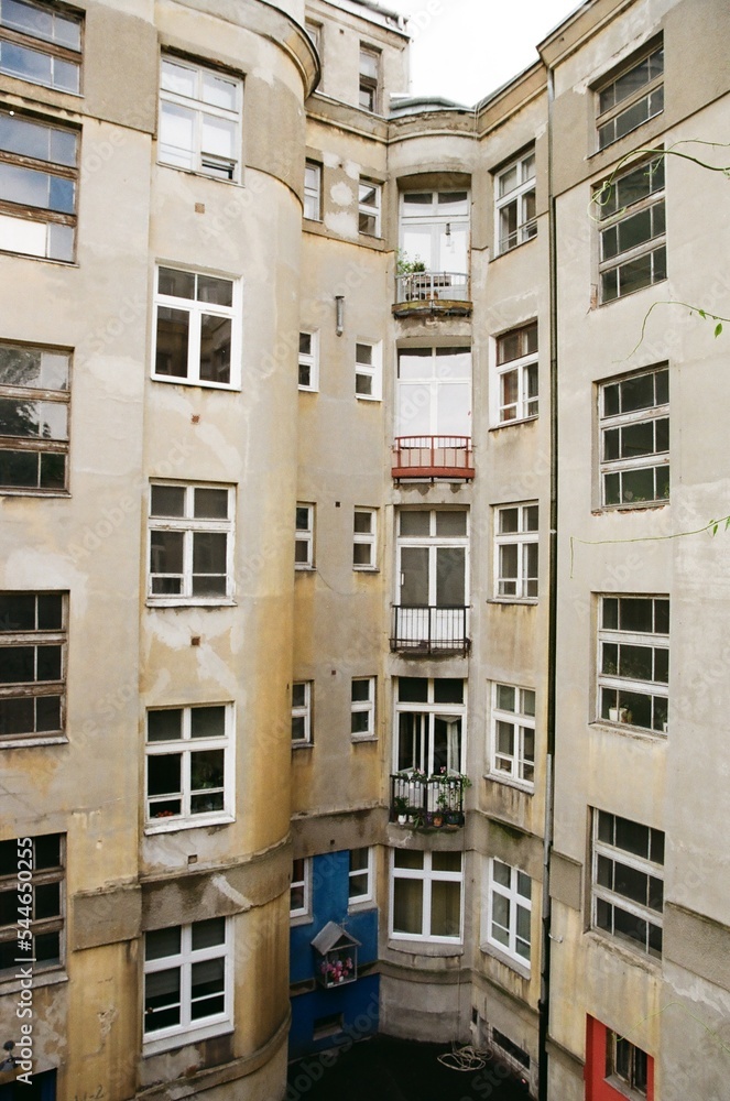 Outdoor shot of the inside of closed estate. Block of flats building with small balconies. Vertical analog photograph taken in Warsaw Praga. High quality photo