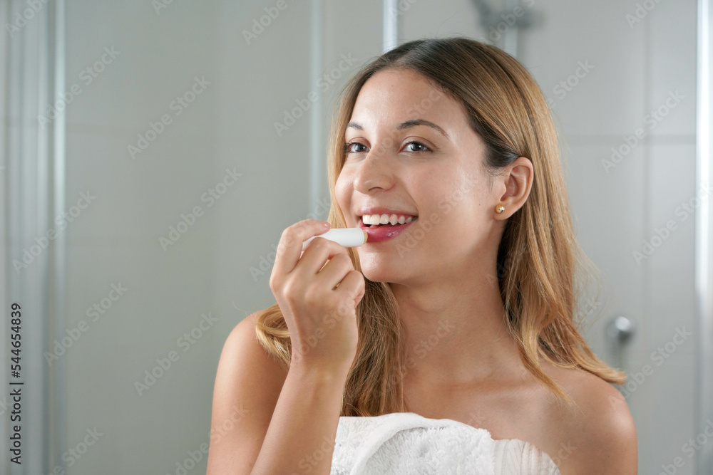 Brazilian girl applying lip balm in front of the mirror indoor Brazilian girl applying lip balm in front of the mirror indoor