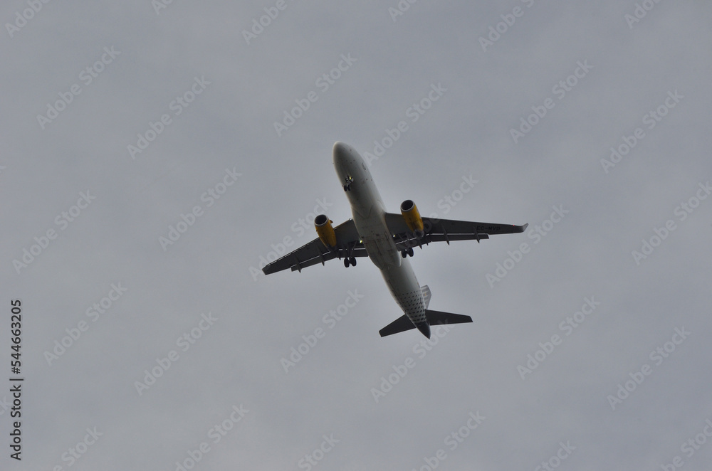 Avión volando con el tren de aterrizaje bajado y un cielo nublado Avión volando con el tren de aterrizaje bajado y un cielo nublado