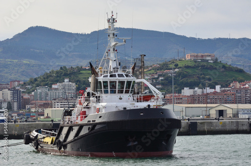 Remolcador atracado en el puerto del municipio de Getxo y al fondo el municipio de santurce photo