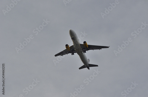 Avión volando con el tren de aterrizaje bajado y un cielo nublado