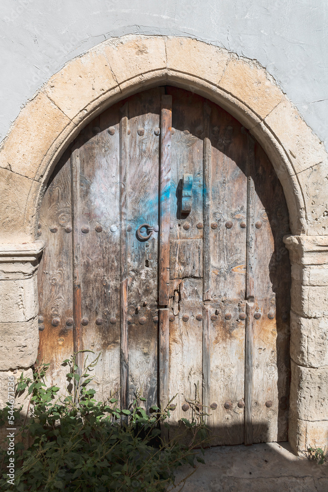 Very old timeworn wooden door in arched stone doorway Very old timeworn wooden door in arched stone doorway