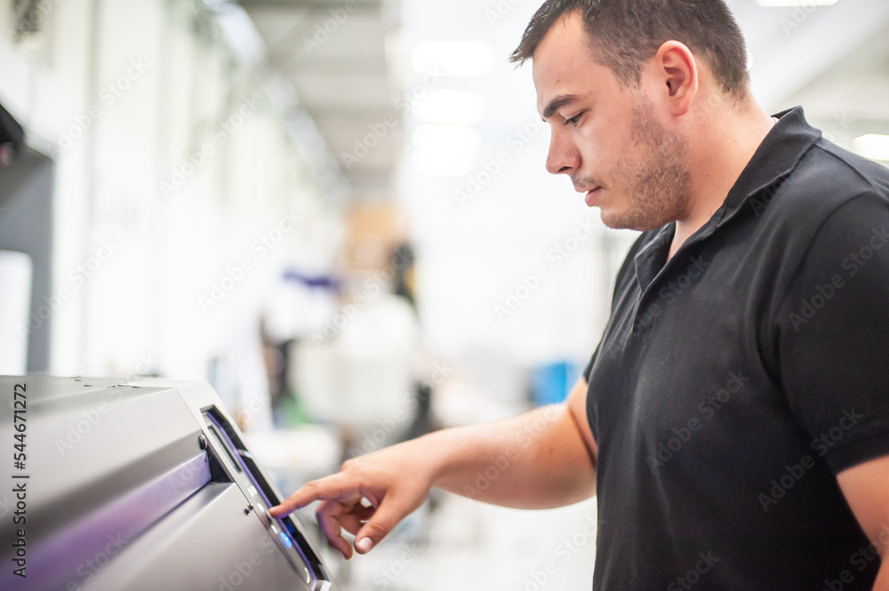 In the printing house, an experienced technician works on a UV printer. Production work. Check the print quality. In the printing house, an experienced technician works on a UV printer. Production work. Check the print quality.