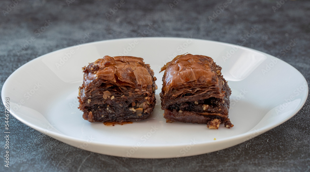 Chocolate baklava in a white plate. Turkish style chocolate baklava presentation and service. Horizontal view. Chocolate baklava in a white plate. Turkish style chocolate baklava presentation and service. Horizontal view.