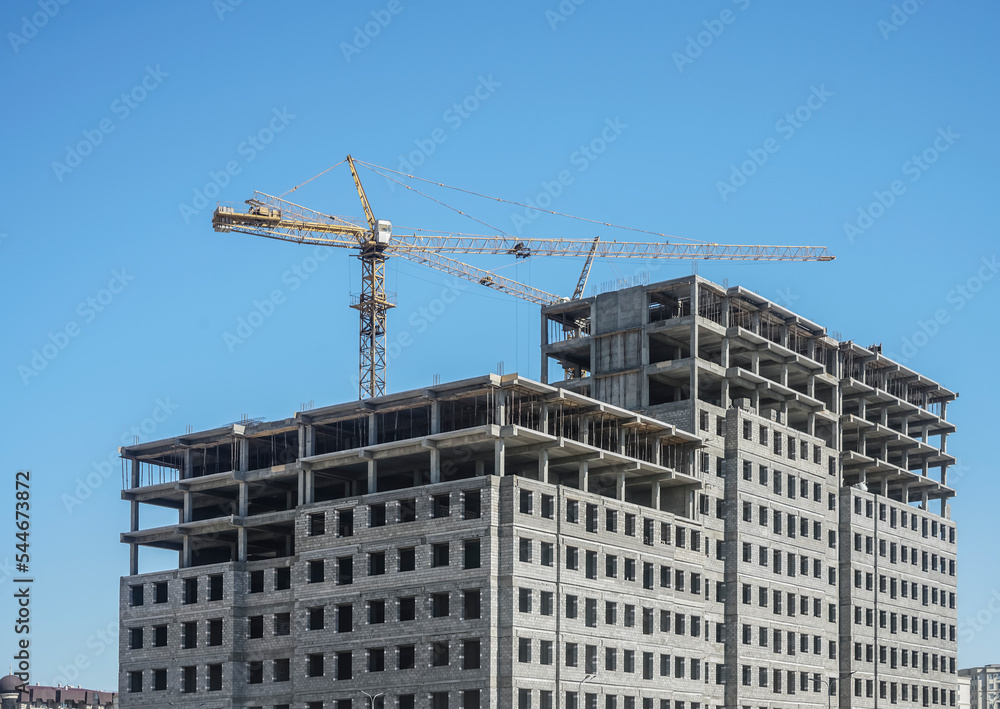Tower cranes and unfinished buildings on background of blue sky with white clouds. Housing construction, apartment blocks in city. Tower cranes and unfinished buildings on background of blue sky with white clouds. Housing construction, apartment blocks in city.