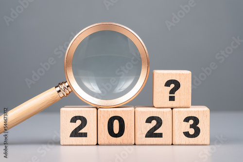 2023 wood cubes with question symbol and magnifying glass, analysis what will happen in 2023, product review and forecast, trend concept