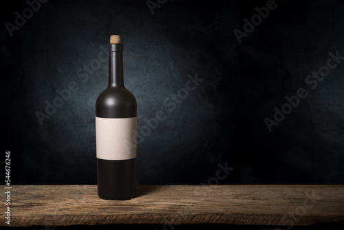 Excellent red wine bottles, wineglass, barrel and corkscrew on a rustic wooden table: traditional winemaking and wine tasting concept. High quality photo